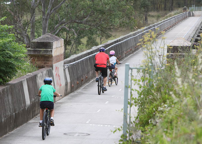 Father and children cycling over a bridge